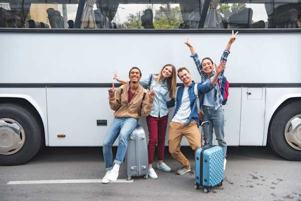 Groupe de voyageurs heureux devant un bus